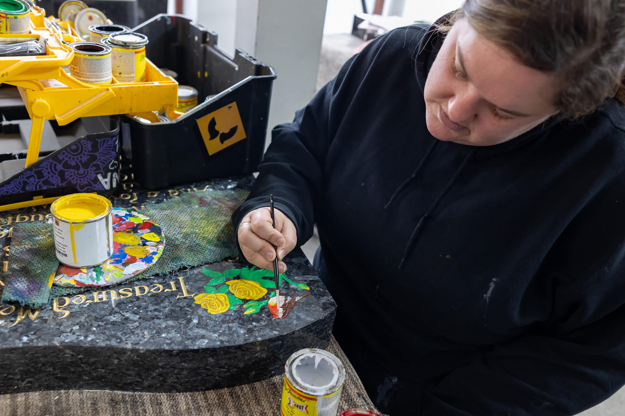 Hand painting into the lettering and intricate designs carved in the stone at Fine Memorials Bridgwater workshop – stonemasons hand-carving headstones and memorials